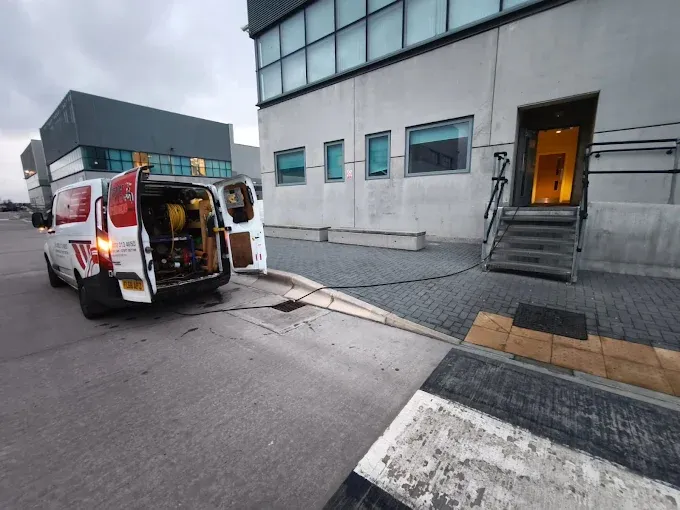 London Drain Experts van with high-pressure jetting equipment running a hose into a drain outside a commercial building